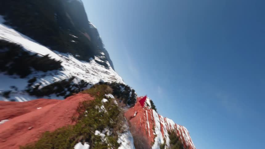 Red flag planted on a snowcovered cliff with a mountainous valley in the background
