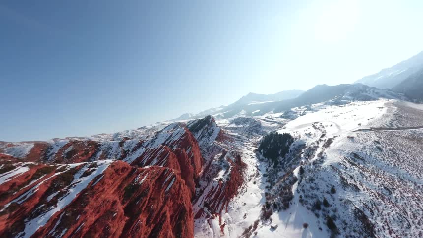 Mountain range with reddish rock slopes and snowcovered areas under a blue sky
