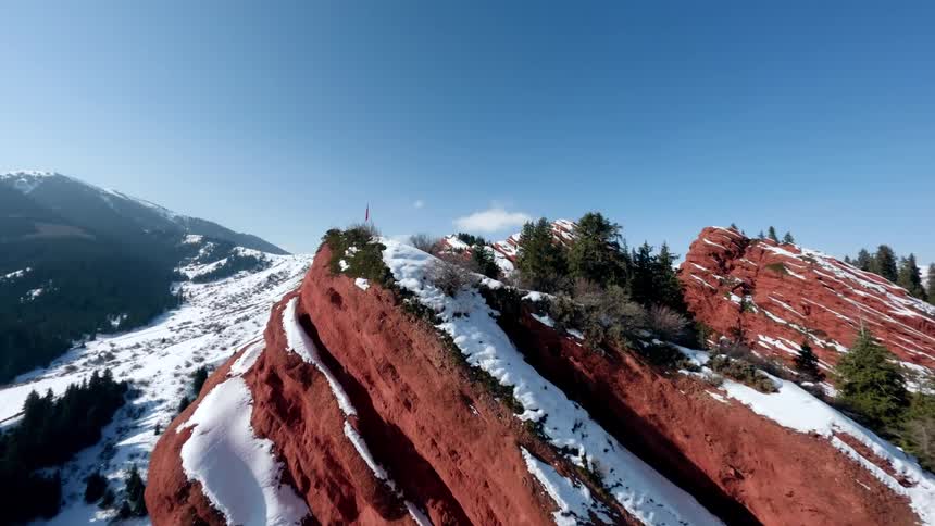 Flag stands near the edge of a cliff in snowy mountainous terrain on a winter day