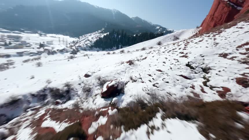 Canyon between reddish rock formations with sections covered in snow