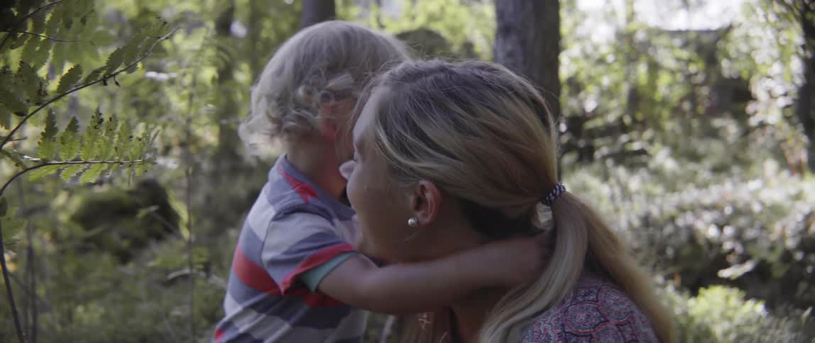 Happy toddler boy and woman sharing an affectionate hug while playing in nature.
