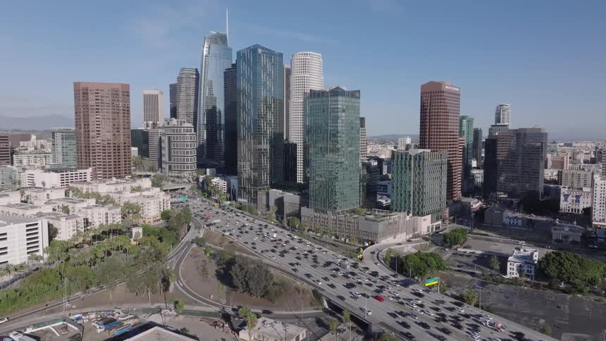 Glass and concrete skyscrapers beside a busy highway in Los Angeles