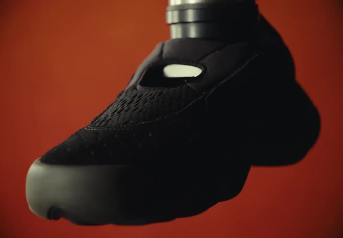 A black sneaker is fitted on the end of a long robotic arm