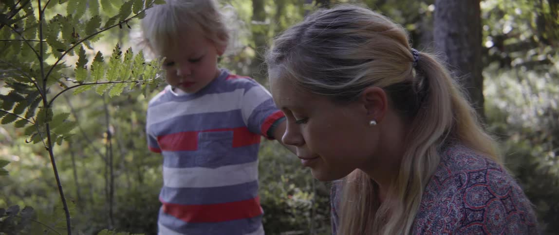 Happy woman and boy spending time together outdoors in a beautiful sunlit woodland.