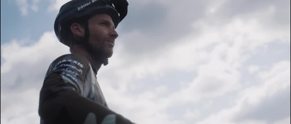 Cyclist wearing a helmet looks toward the horizon under a partly cloudy sky