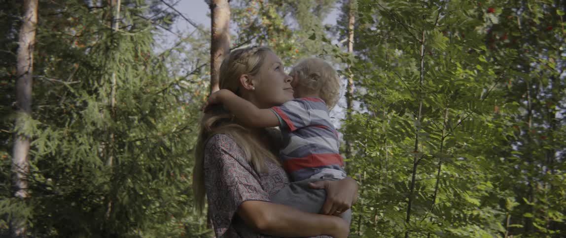 A young woman hold a small child that hugs her and plays with her hair