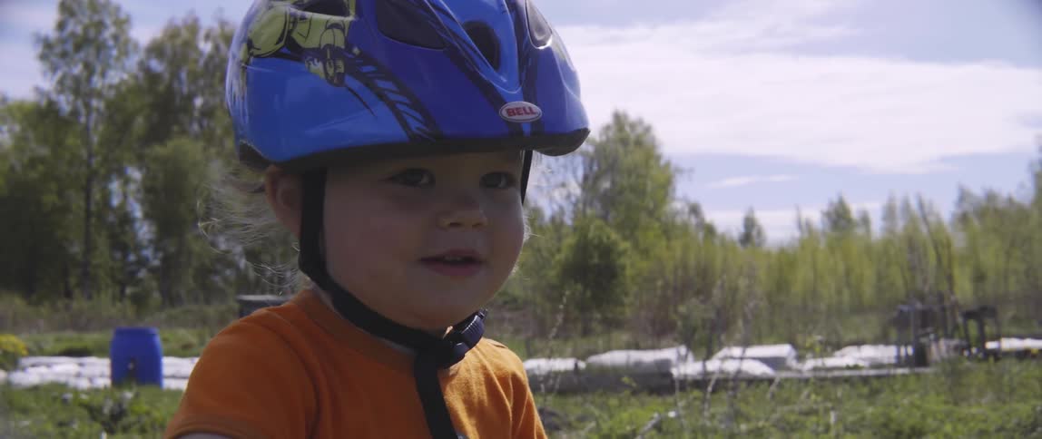 A young boy wears a bicycle helmet and rides a balance bike