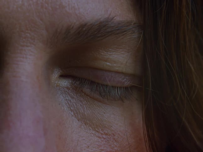 Closeup of a womans eye with hair partially covering her face