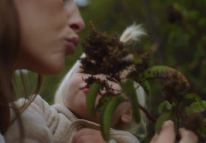 The child and mother smell a flower