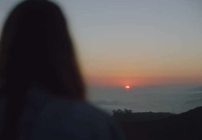 Person watches the sunset over distant mountains