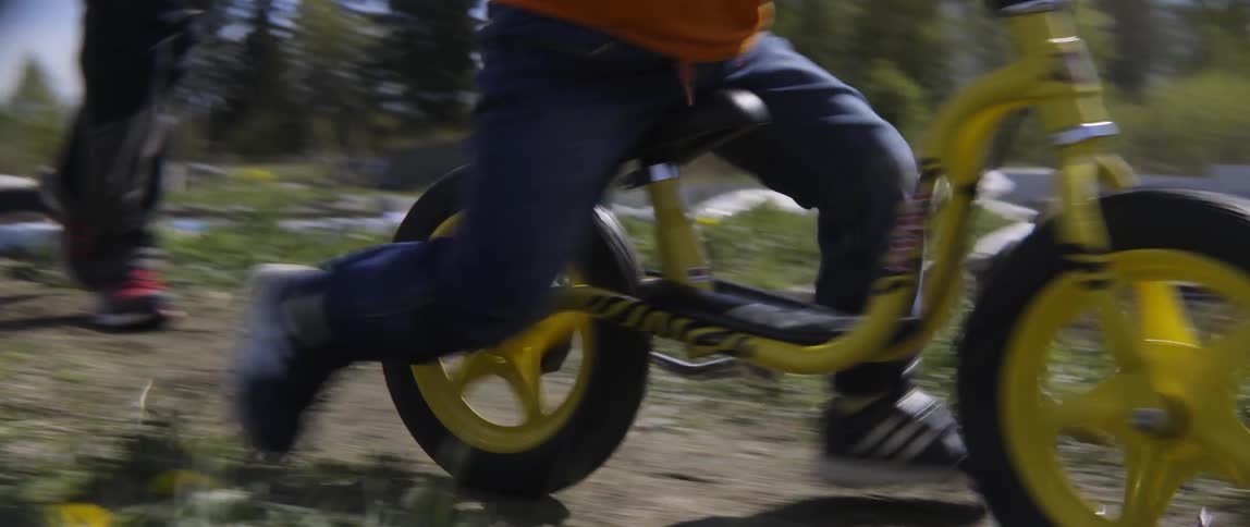 Small child pedaling his bike on a bright and sunny day at the park.