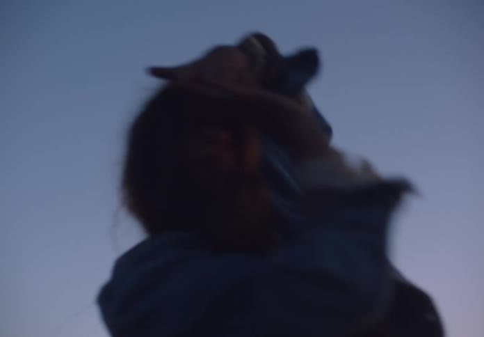 A young woman dancing outdoors at sunset while wearing a jacket