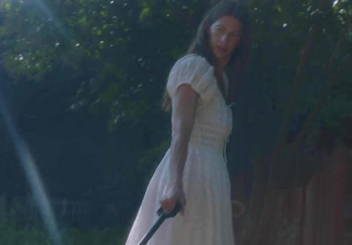 A woman in a white dress pulls a toddler in a red wagon behind her