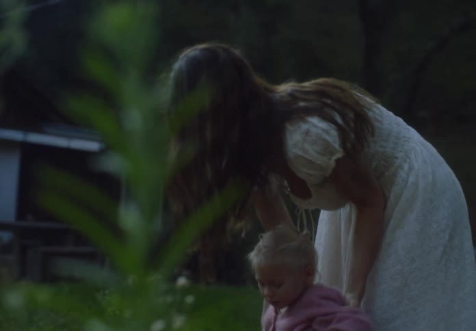 Mother holds her daughter in her arms while they play outdoors