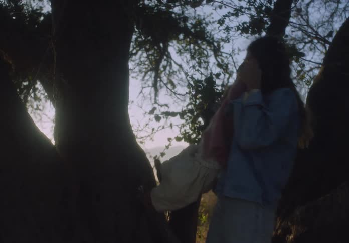 Mother helps her daughter move her feet up a tree on a sunny autumn day