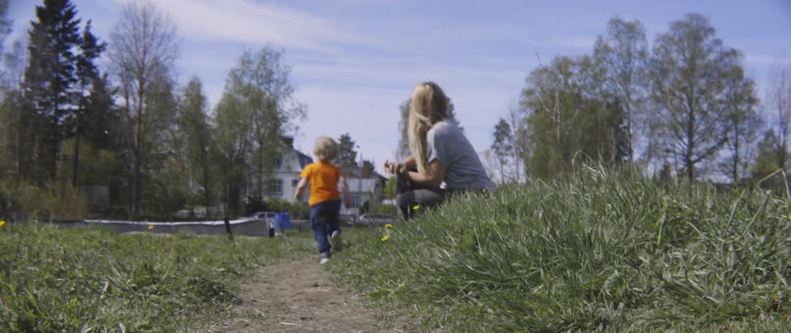 Toddler running past his mother on a thin trail on a cloudy day