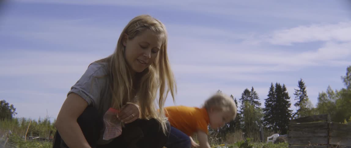 Mother and young son working in the dirt to plant seeds outdoors together.