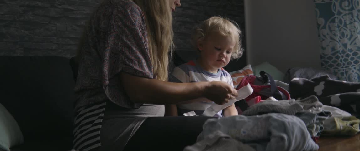 Mother and toddler boy looking at a colorful book together in a bright home.