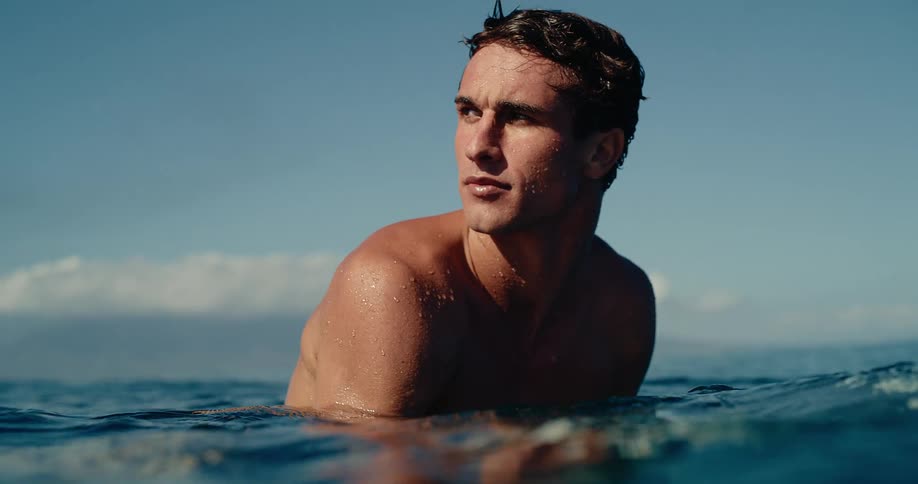 Man with his torso out of the ocean looking to the right