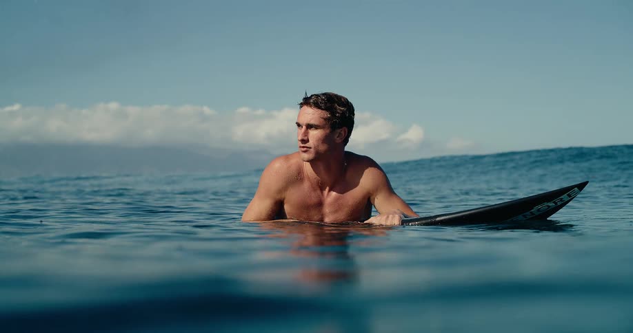 Surfer holding a surfboard while floating in the ocean