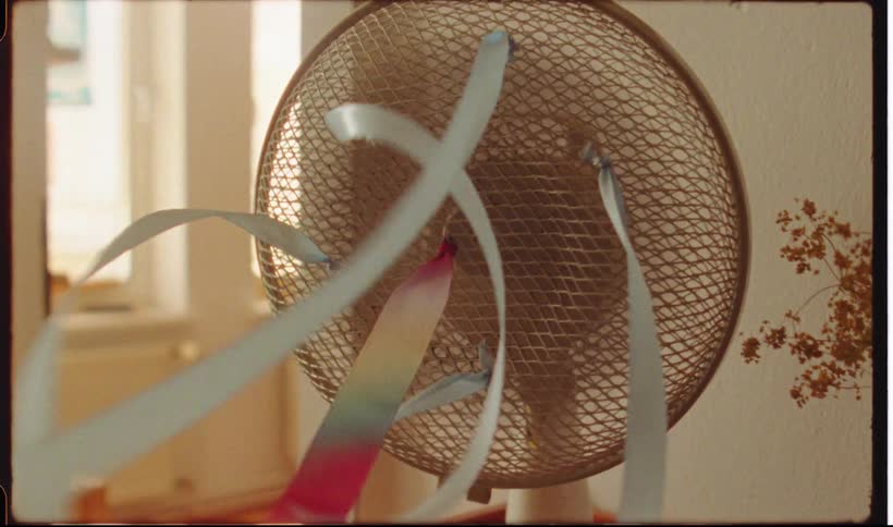 Colorful ribbons attached to a fan spinning indoors