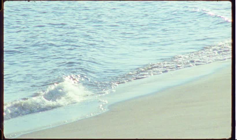 Sea waves reaching the sand along the beach shoreline