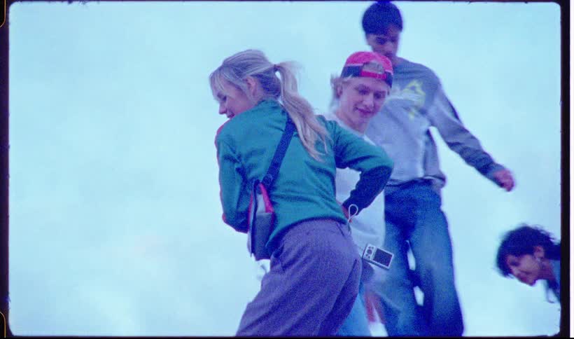 Young people helping a woman climb an outdoor structure under cloudy skies