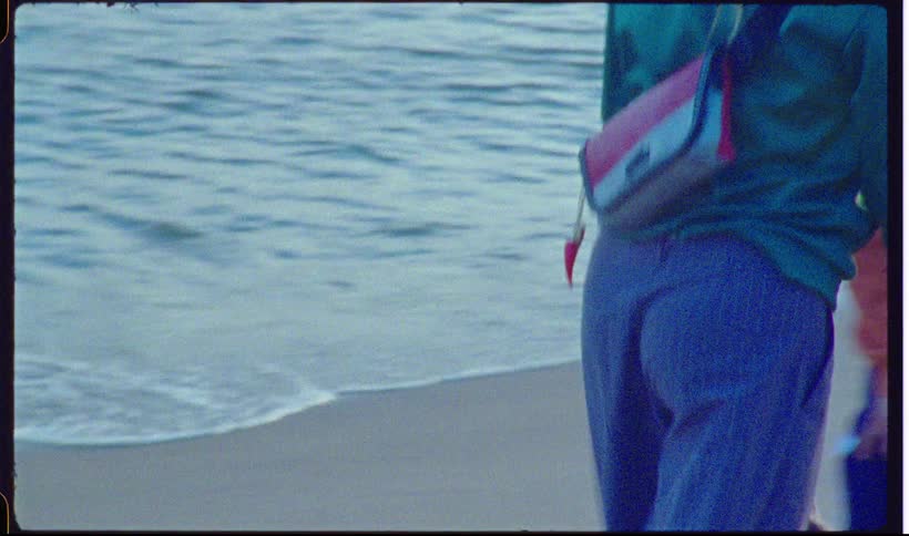 Three young adults smile as they have fun while walking on the beach