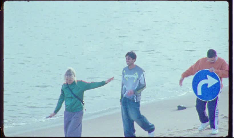 A group of people walking on the beach carrying a sign