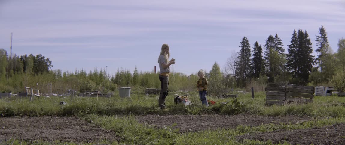 Woman standing in a field with a toddler on a cloudy day