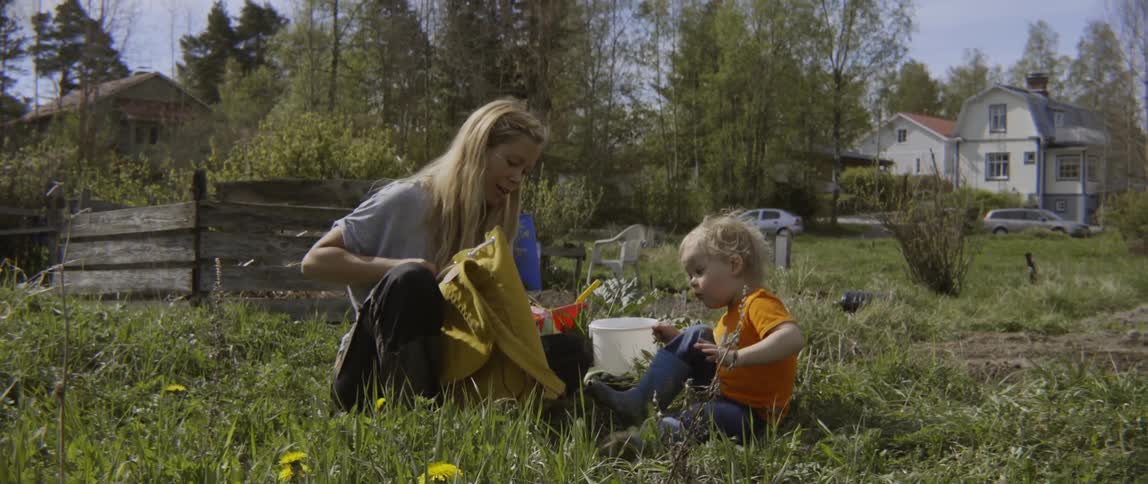 A woman and young boy sitting together in a lush green grassy area.
