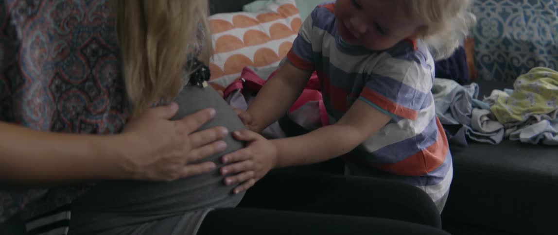 Expectant mother and toddler boy sharing a tender moment together in a bright space