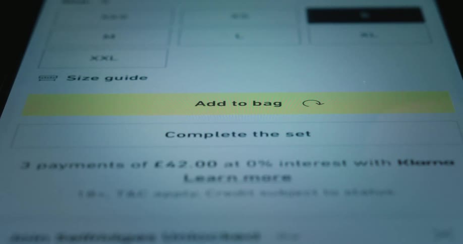 A finger taps a yellow button on a smartphone screen to add a product to a digital shopping cart before a confirmation message appears