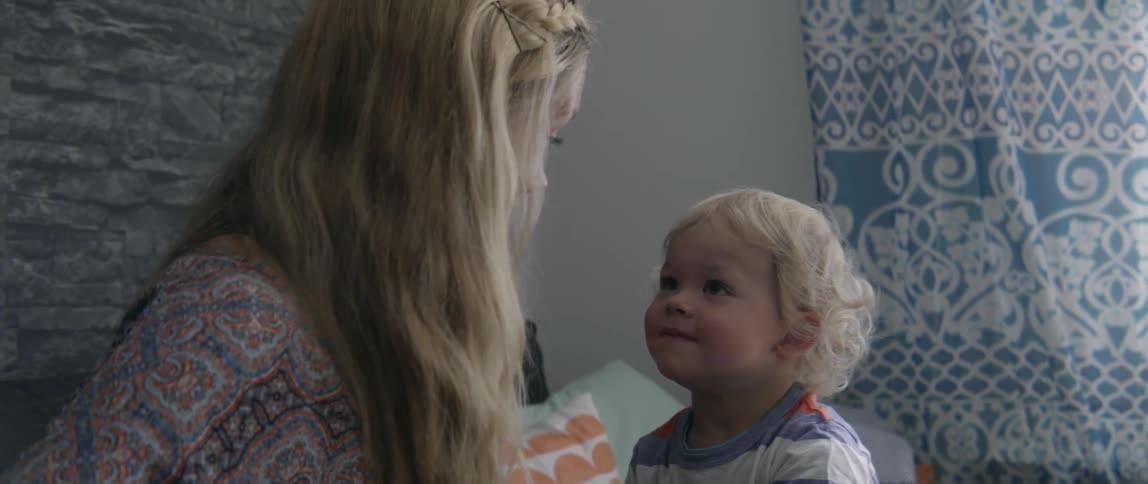 Toddler boy smiles as his pregnant mother talks to him in living room