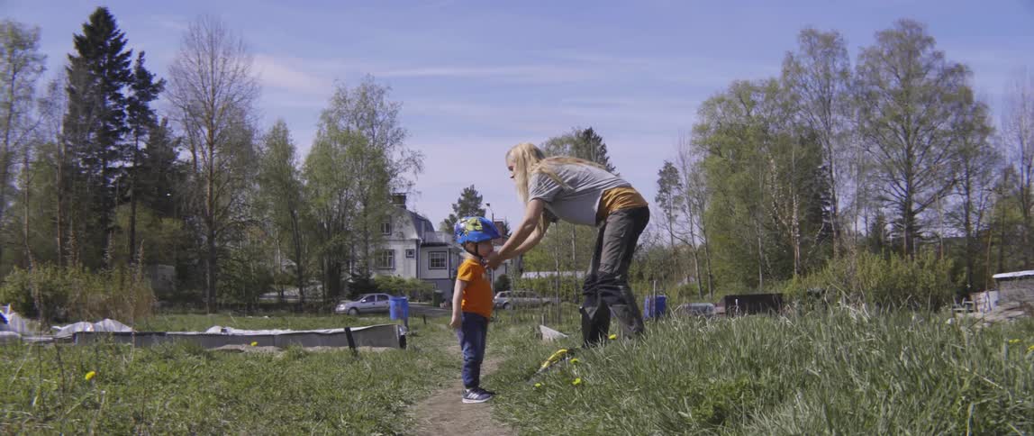 A woman is helping a boy remove his helmet after riding his bike
