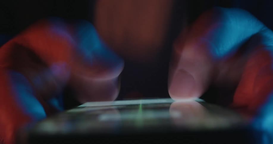 Extreme closeup of hands rapidly scrolling on a smartphone screen in low light
