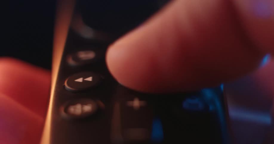 A persons finger pressing a button on a remote