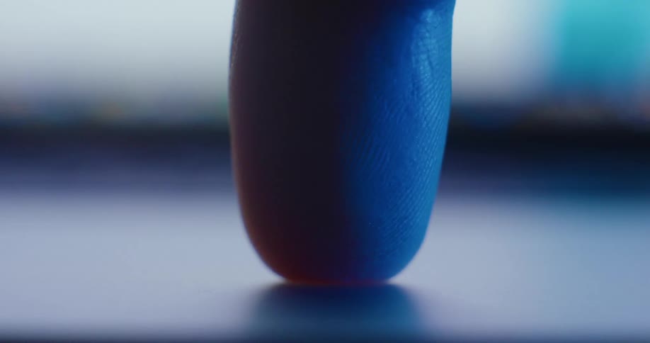 Extreme closeup of a fingertip touching a glowing screen in low light