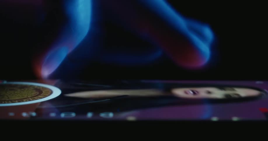 A close view from the side of a person using a finger to scroll through various colorful advertisements on a mobile phone screen in a dark room