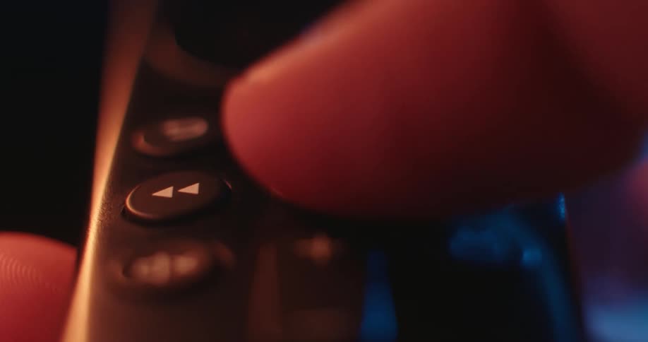 Closeup of an adult thumb pushing a button on a remote control