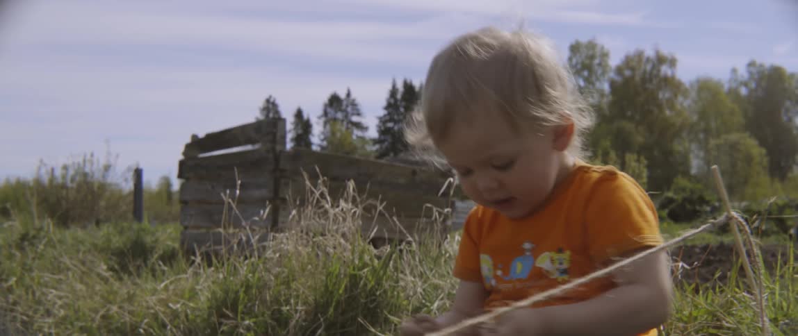 Toddler boy playing outside in the dirt on sunny day