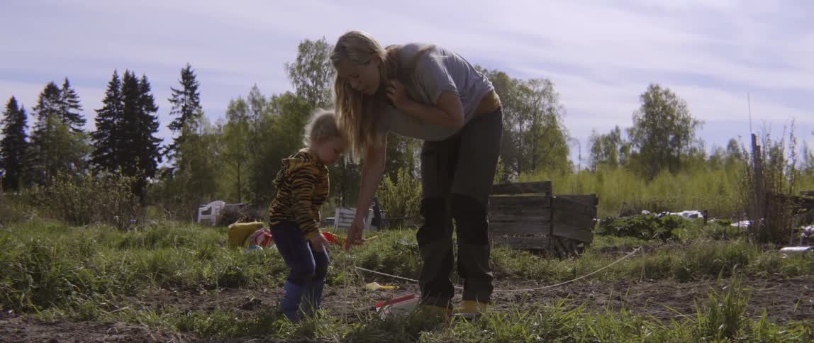 Mother and young son gardening together outdoors during a bright and sunny afternoon.