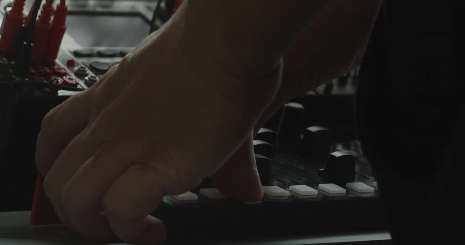 A person in a studio operating musical equipment with his hands