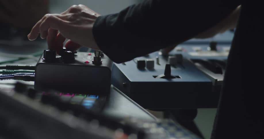 Two people adjust settings on a piece of audio equipment and a keyboard
