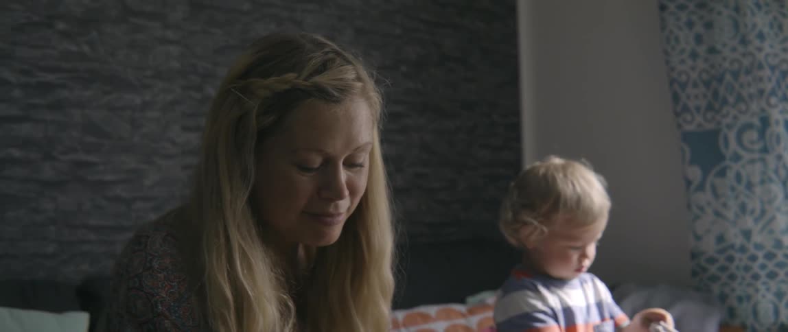 A woman and her toddler child are sitting in a living room