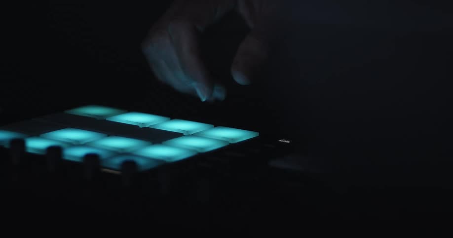 Fingers pressing illuminated pads on a music controller