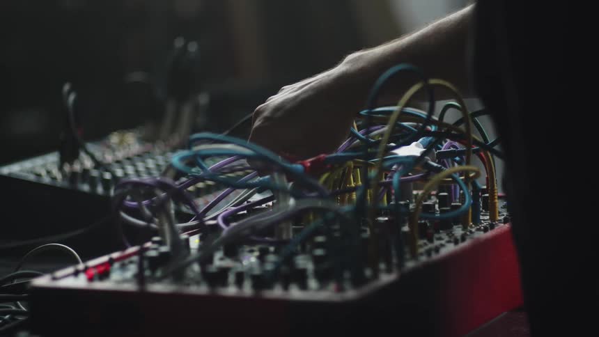 Mans hand pulls a cable on a soundboard