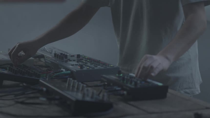 Person adjusting controllers and electronic music equipment on a table