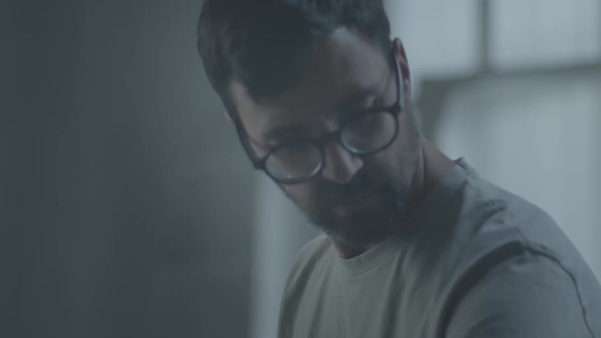 A determined music producer working on recording in a softly lit indoor studio
