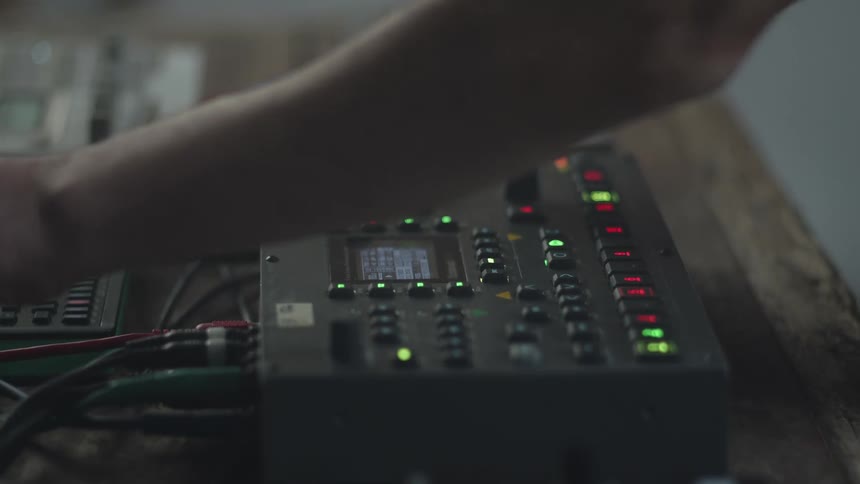 An adult rapidly adjusts a sound mixer board